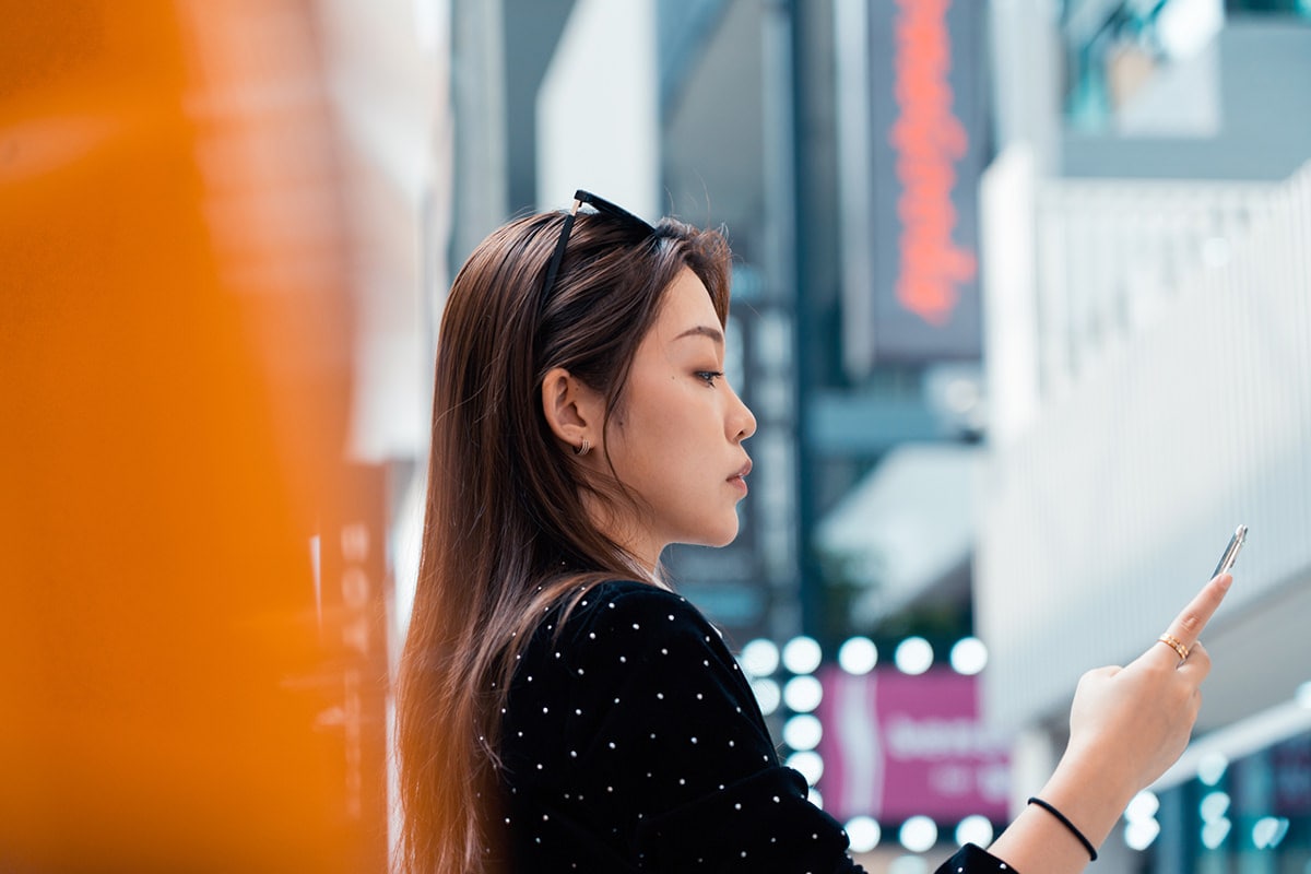 Woman on a city street looks at programmatic ad on her smartphone